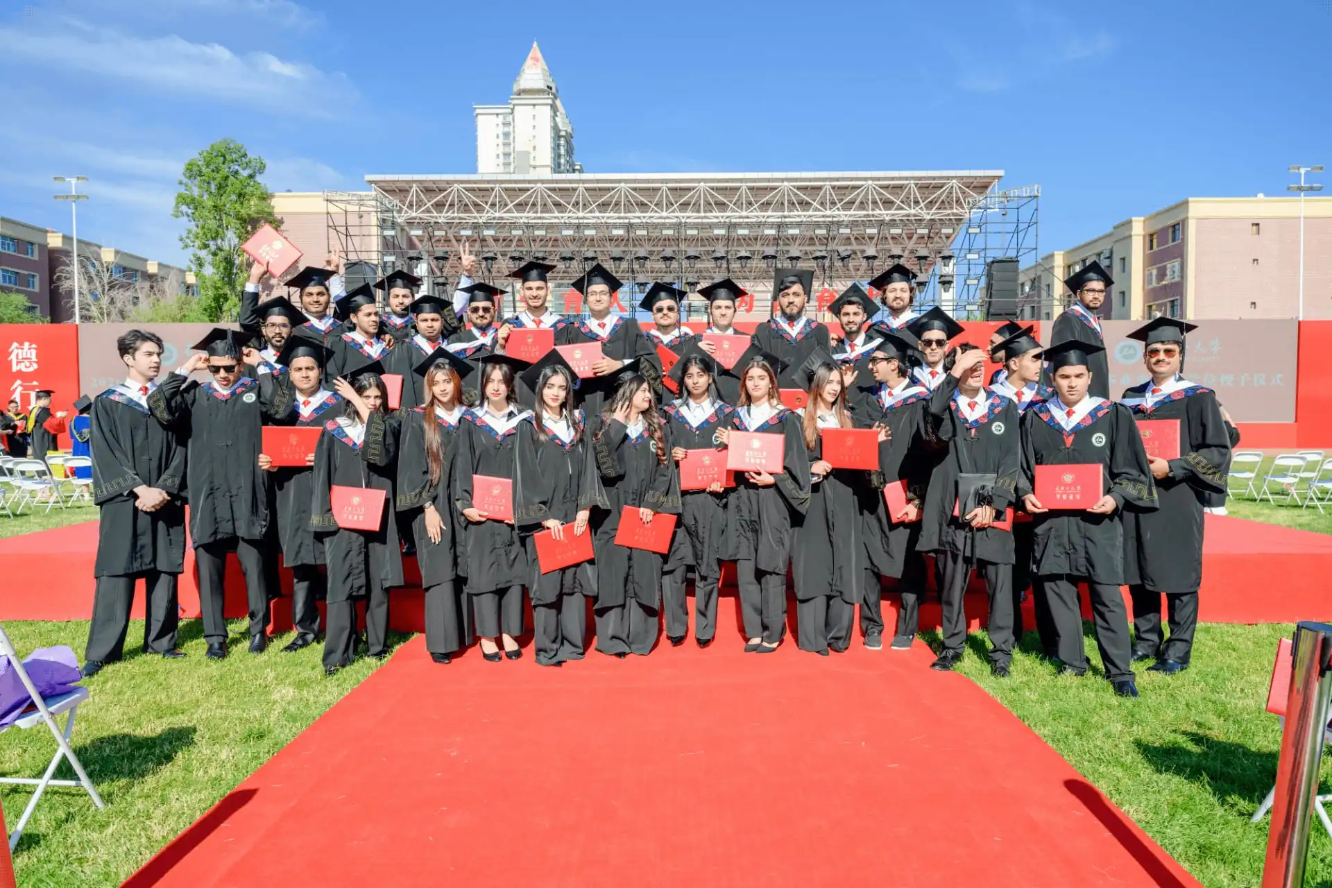Graduates posing together on red carpet at university graduation ceremony