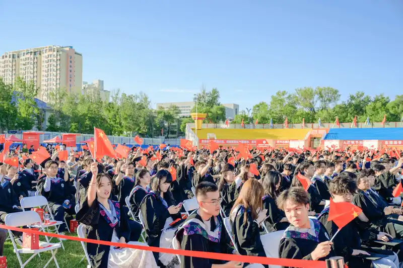 Wide view of outdoor graduation ceremony with large crowd of students