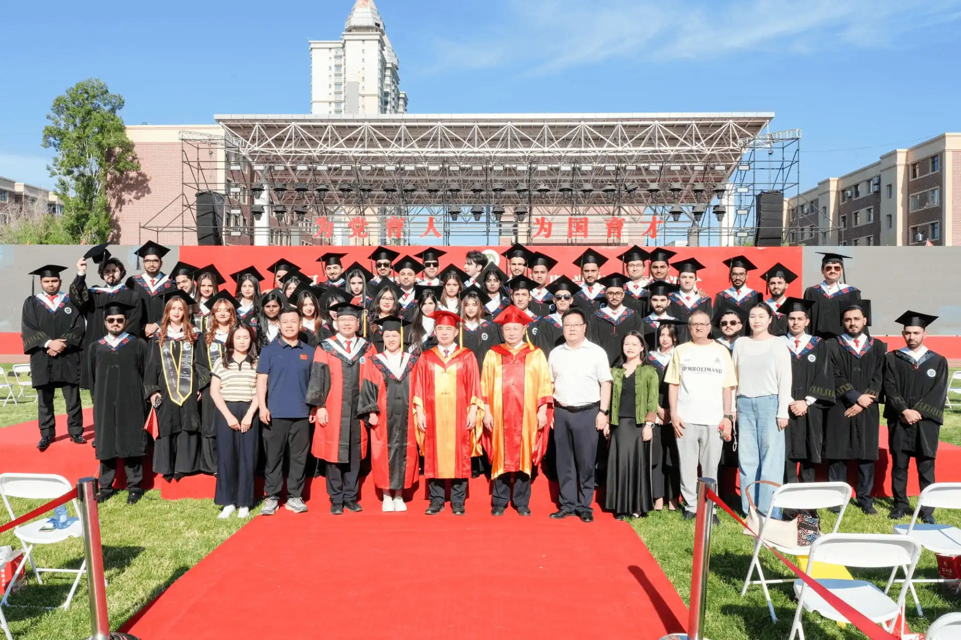 International graduates standing on red carpet outdoors during commencement