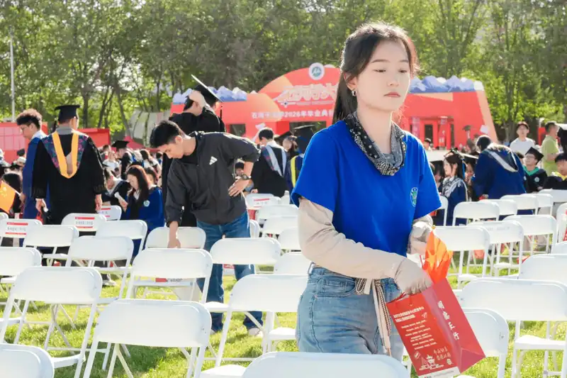 Student in graduation gown posing outdoors on campus lawn