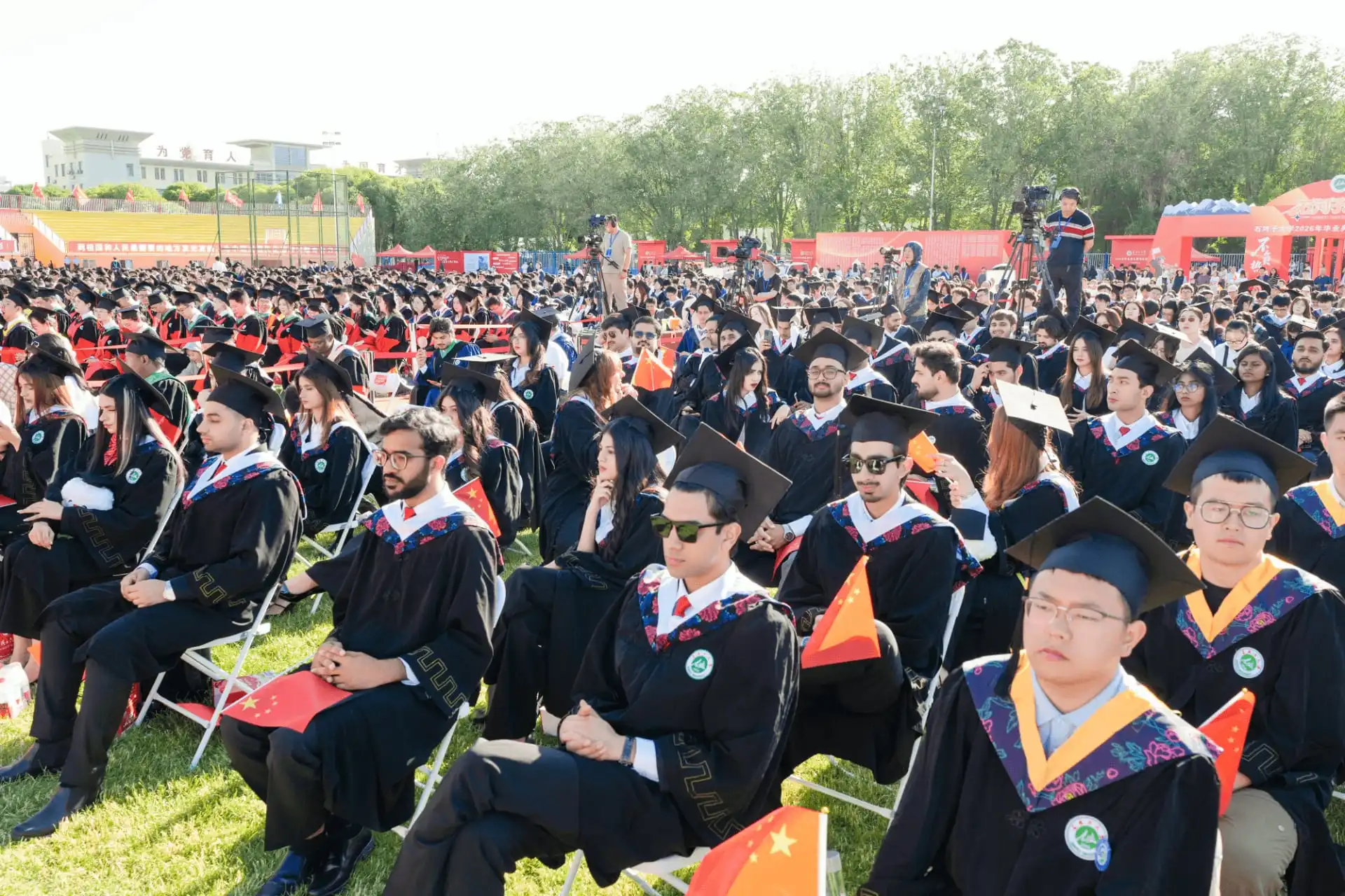 Seated university graduates wearing black academic caps and gowns