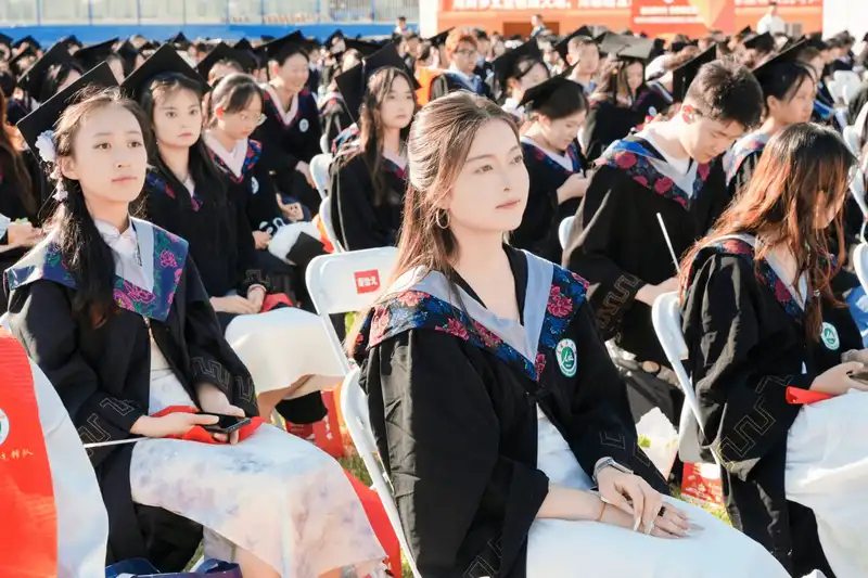 Crowd of university graduates sitting together during outdoor ceremony